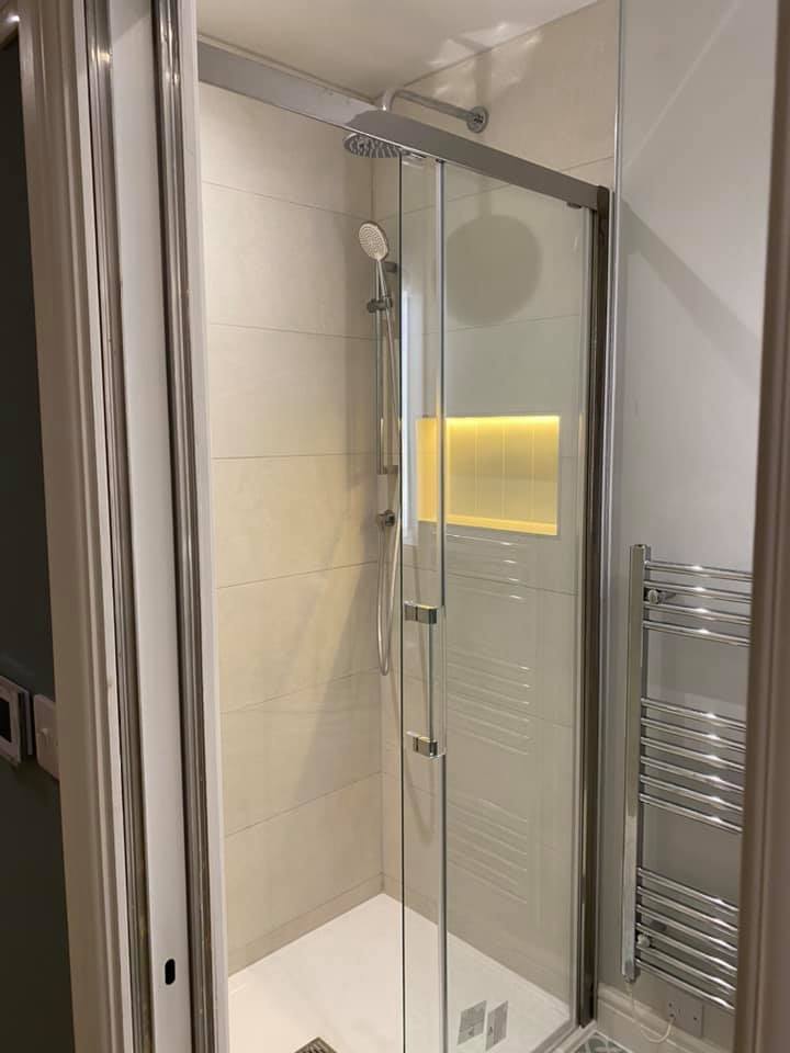 Shower enclosure with a lit niche and chrome towel radiator