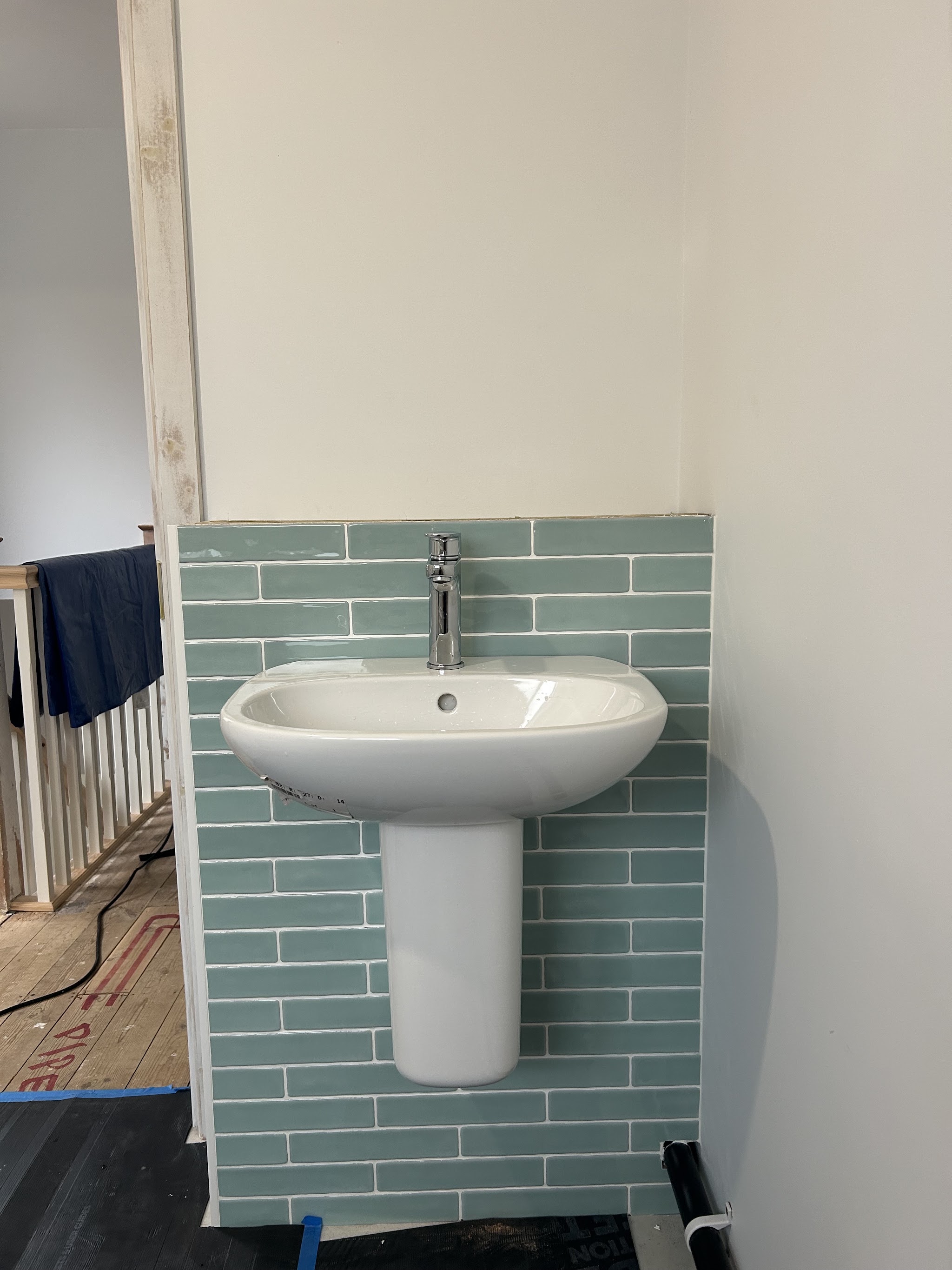Basin on a green tiled splashback