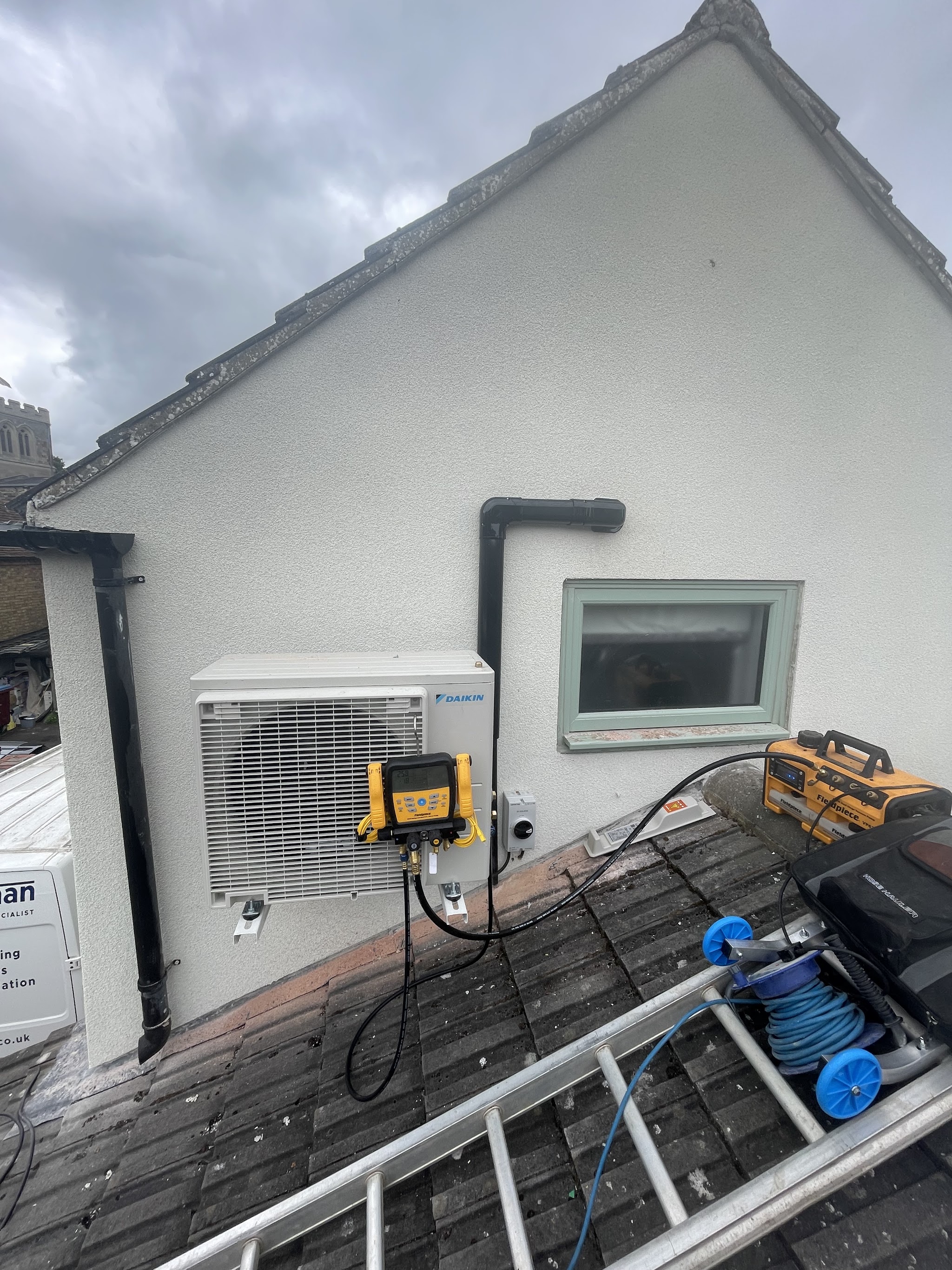 Air conditioning outdoor unit being fitted to the wall of a house