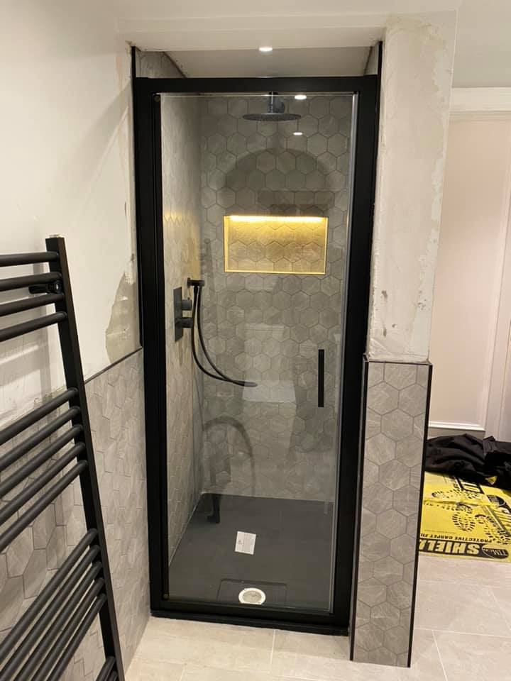 Black framed shower enclosure with a lit tiled niche