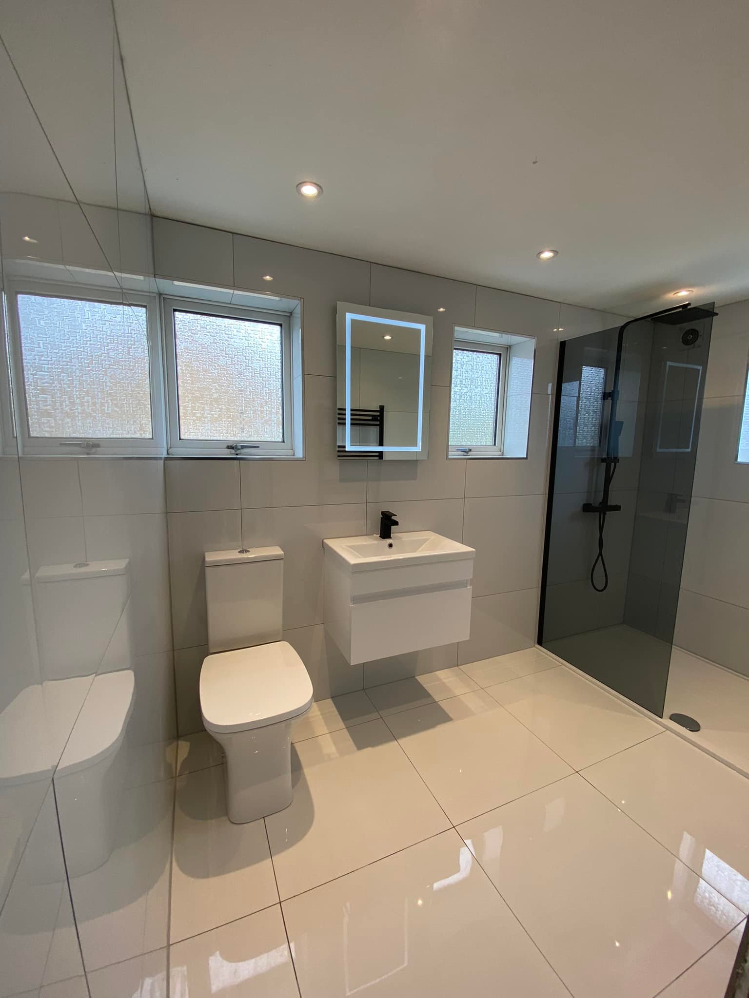 Large bathroom with a walk-in smoked glass shower, wall-hung basin and LED mirror