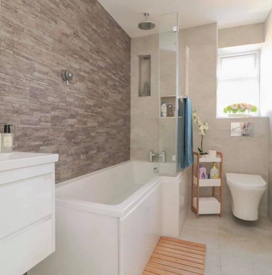 Bathroom with an L-shaped bath and a stone effect feature wall