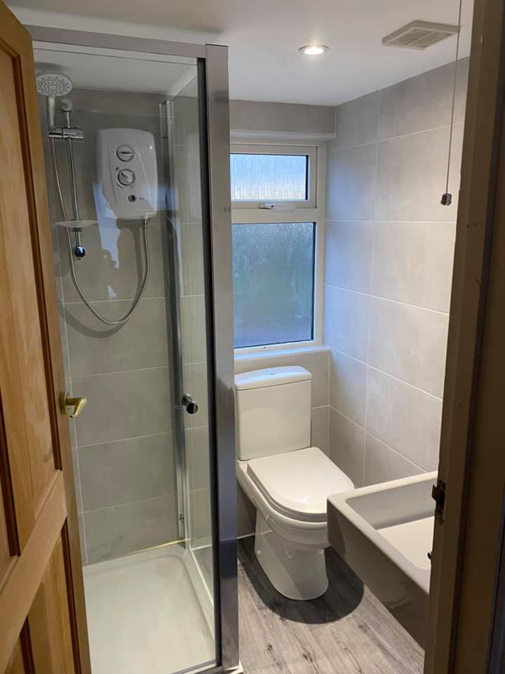 Shower room with an electric shower and grey tiling